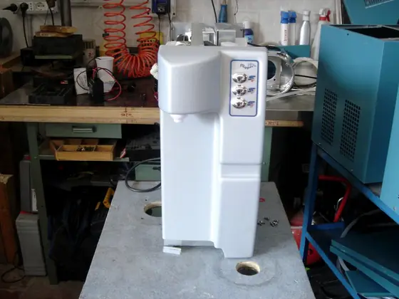 Un erogatore d'acqua bianco con tre pulsanti, appena revisionato sul banco dell'officina.