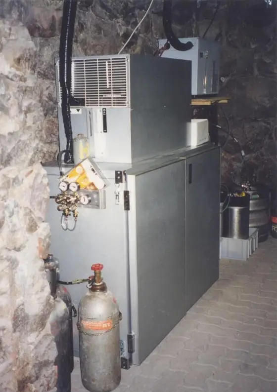 Un refrigeratore per birra con la bombola di CO₂ accanto, in una cantina con le pareti di pietra.