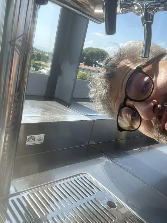 Un tecnico con gli occhiali sbuca da sotto il banco d'acciaio, accanto alla colonna appena montata.